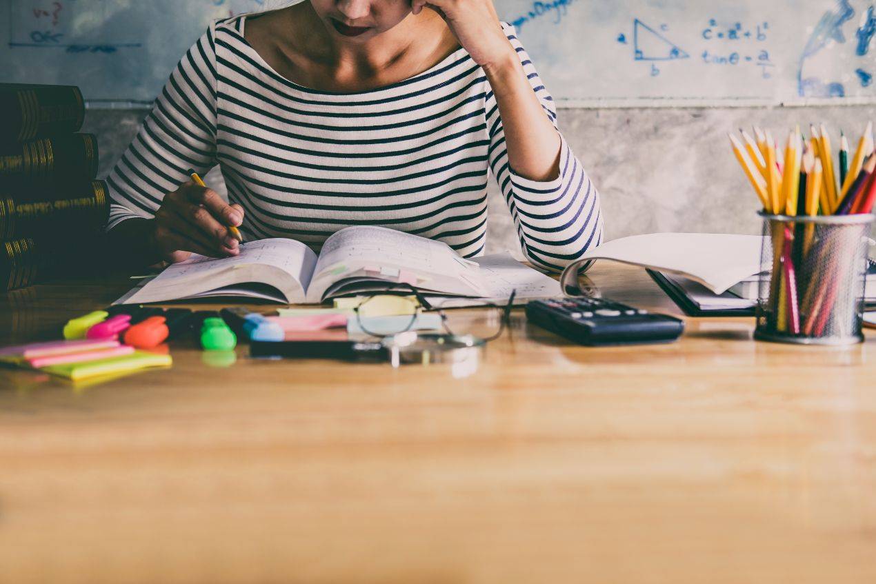 Studentin arbeitet konzentriert an ihrer bachelorarbeit mit ghostwriter bachelorarbeit unterlagen und textmarkern